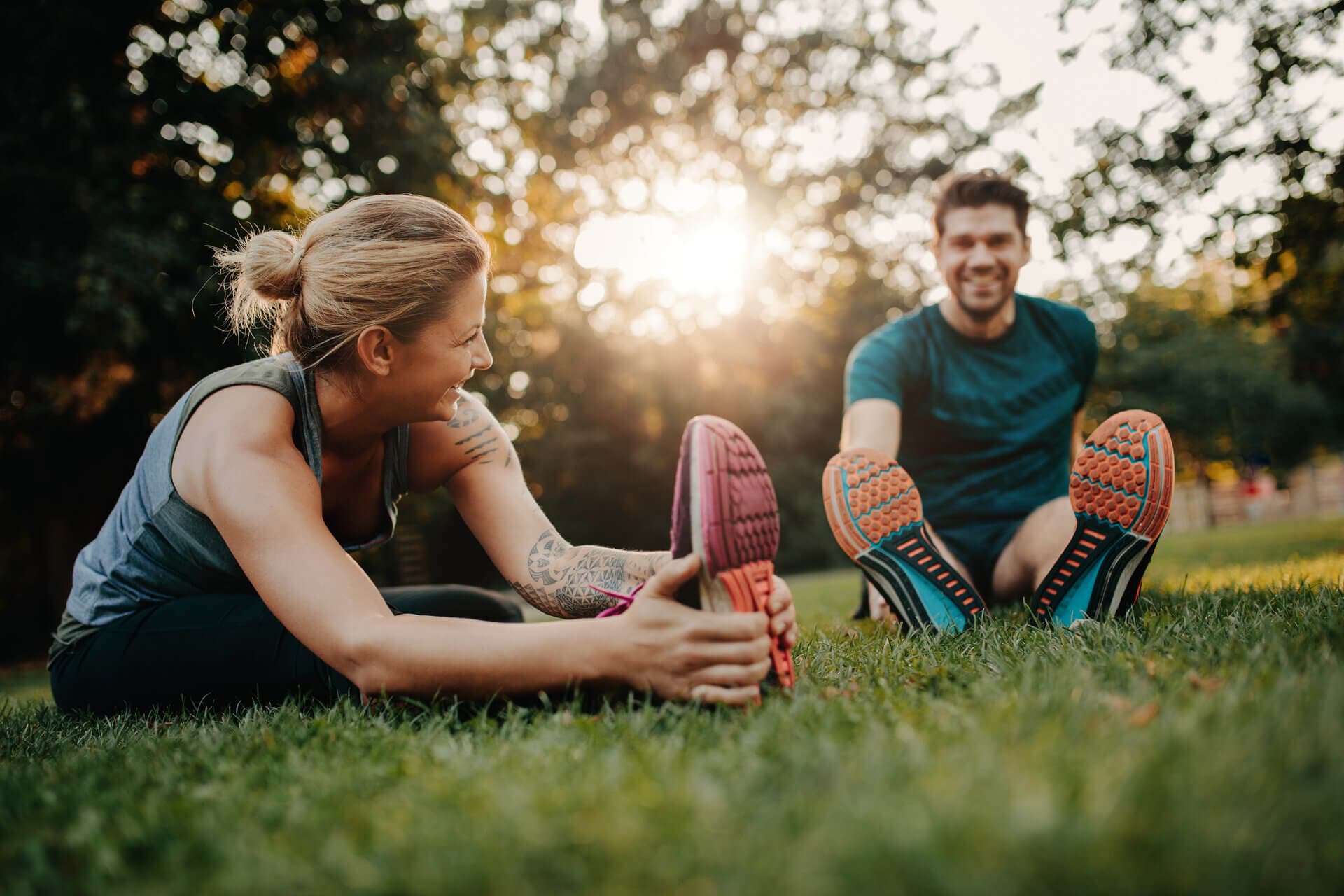 two people performing leg stretches in a park