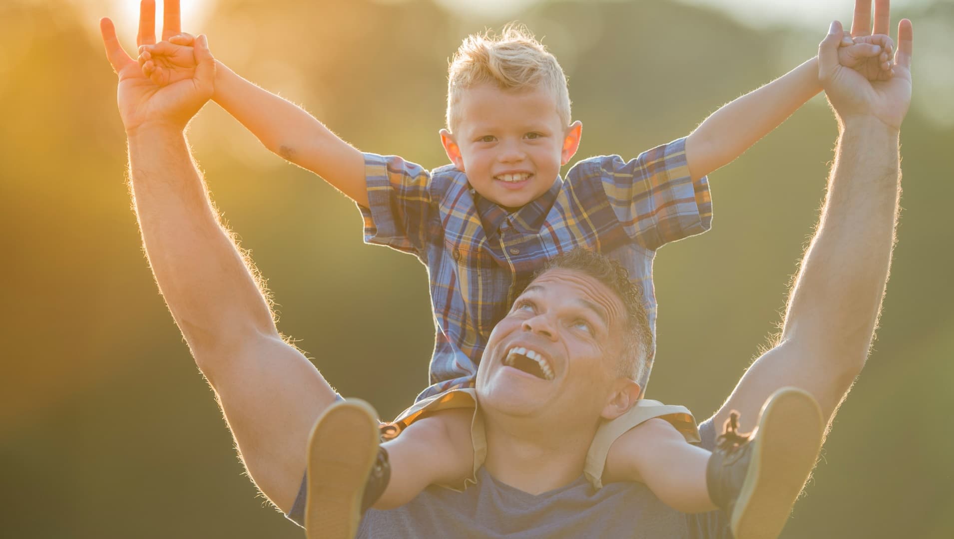 A father laughs with his sun sat happily on his shoulders