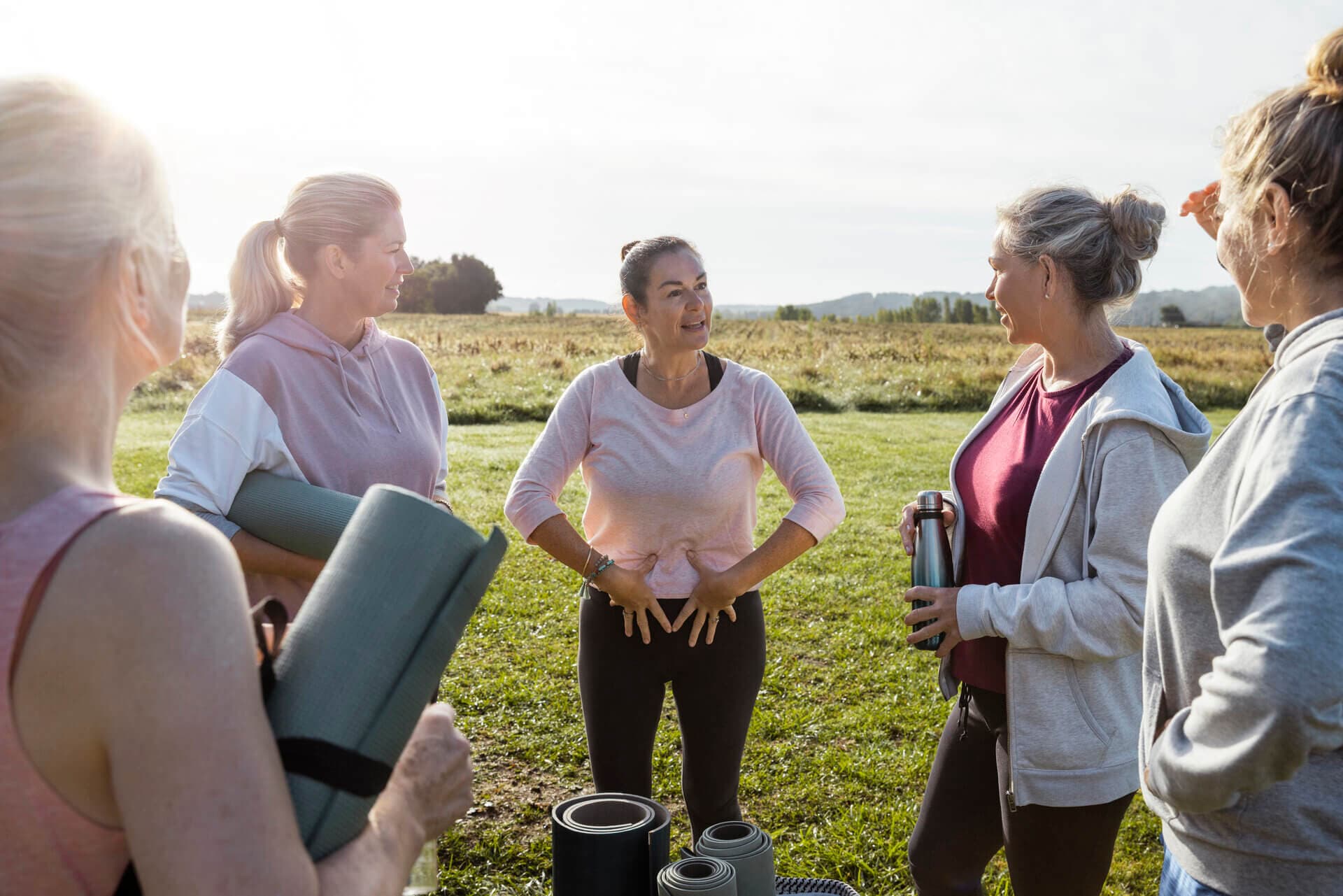 Group of women with a leader demonstrating with their hands on their abdomen