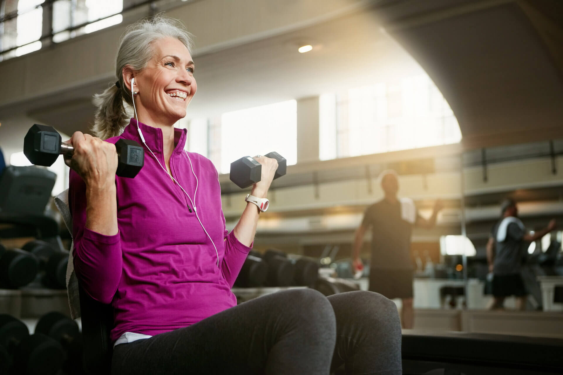 Older lady joyfully lifting weights in a gym