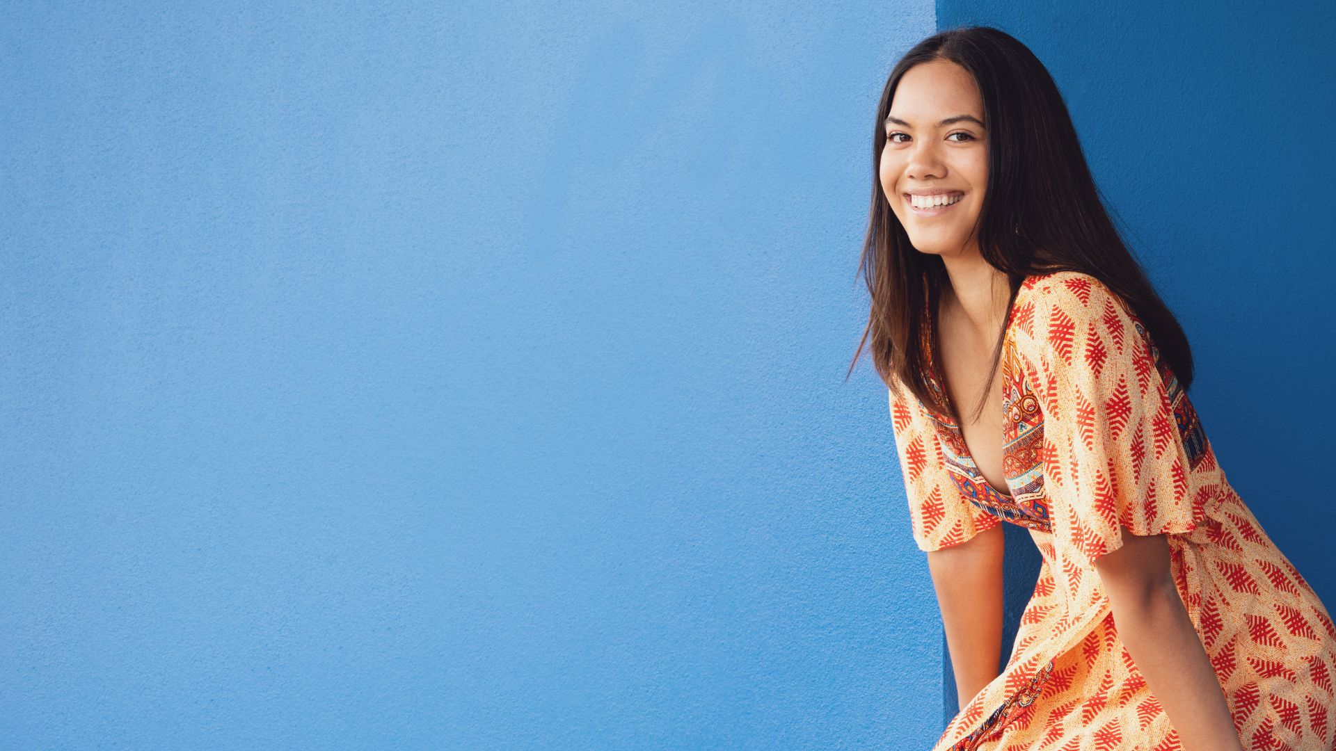 Maori woman smiles against a blue wall