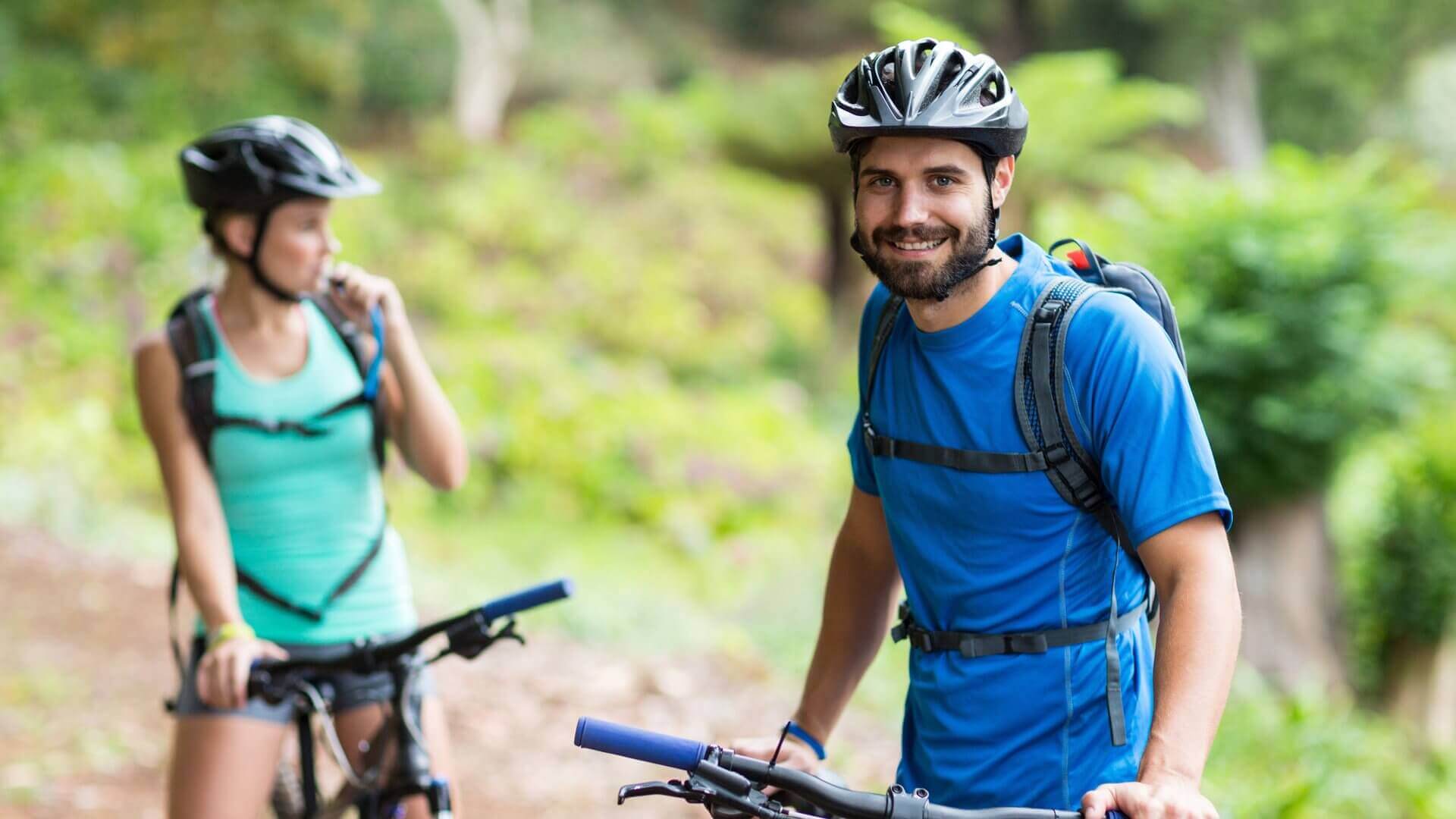 Person smiling happily in the woods bike riding
