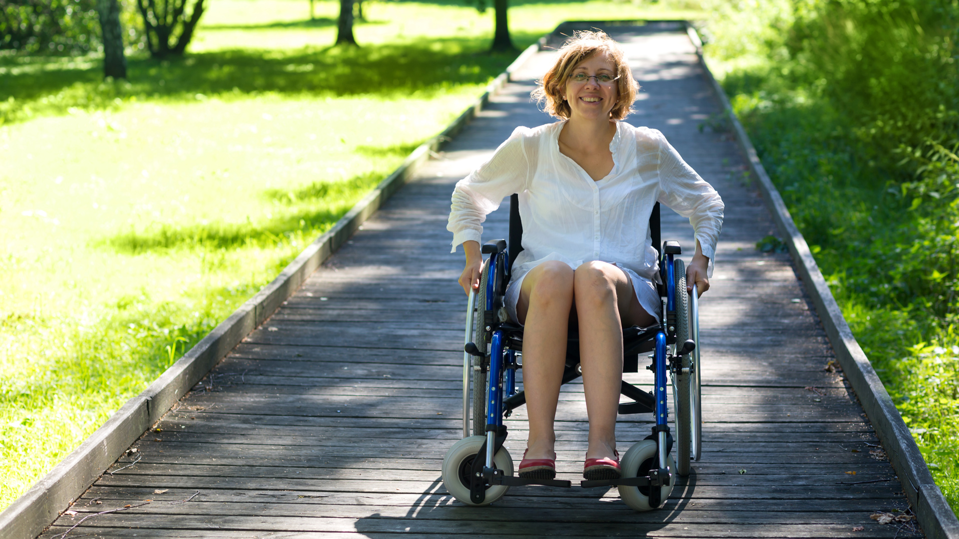 woman in a wheelchair on a bridge in the park