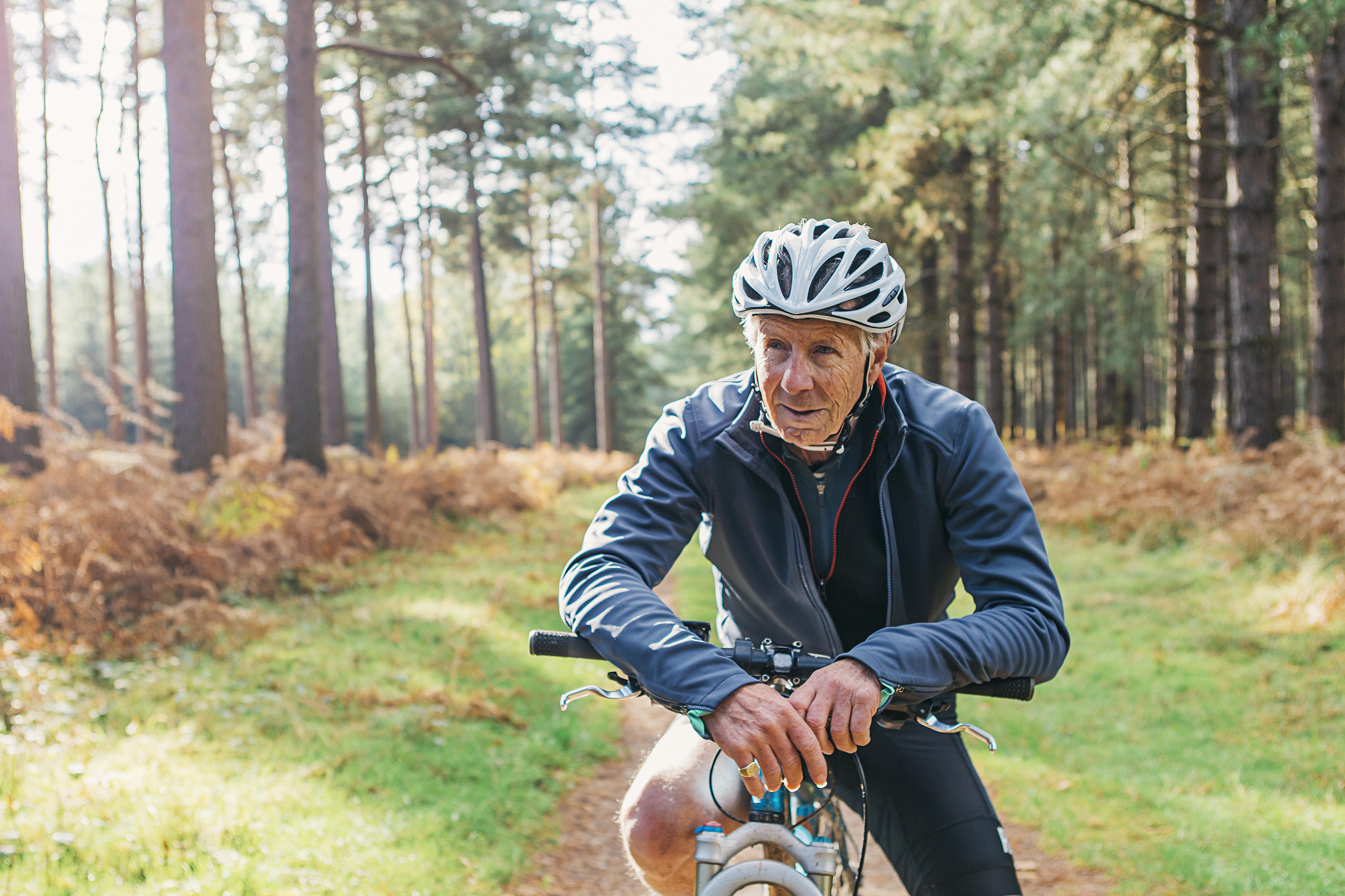 Older man riding a bicycle in a scenic forest