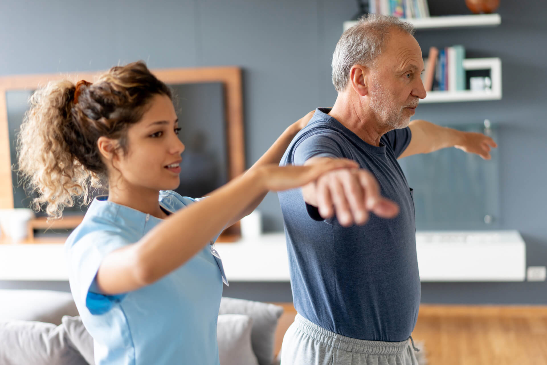 Physio guides as an older man raises his arms