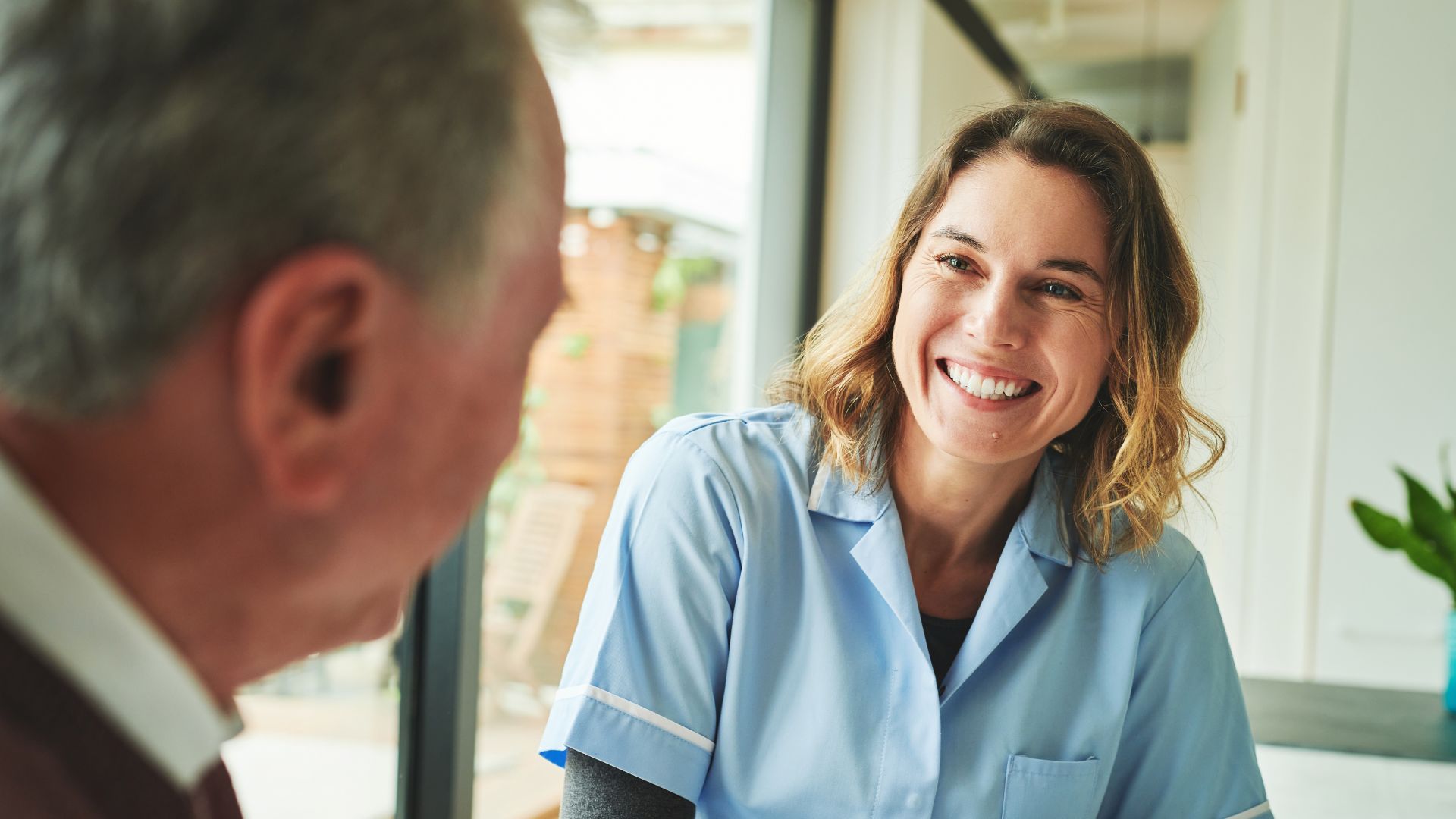 Aged care nurse smiles with older patient